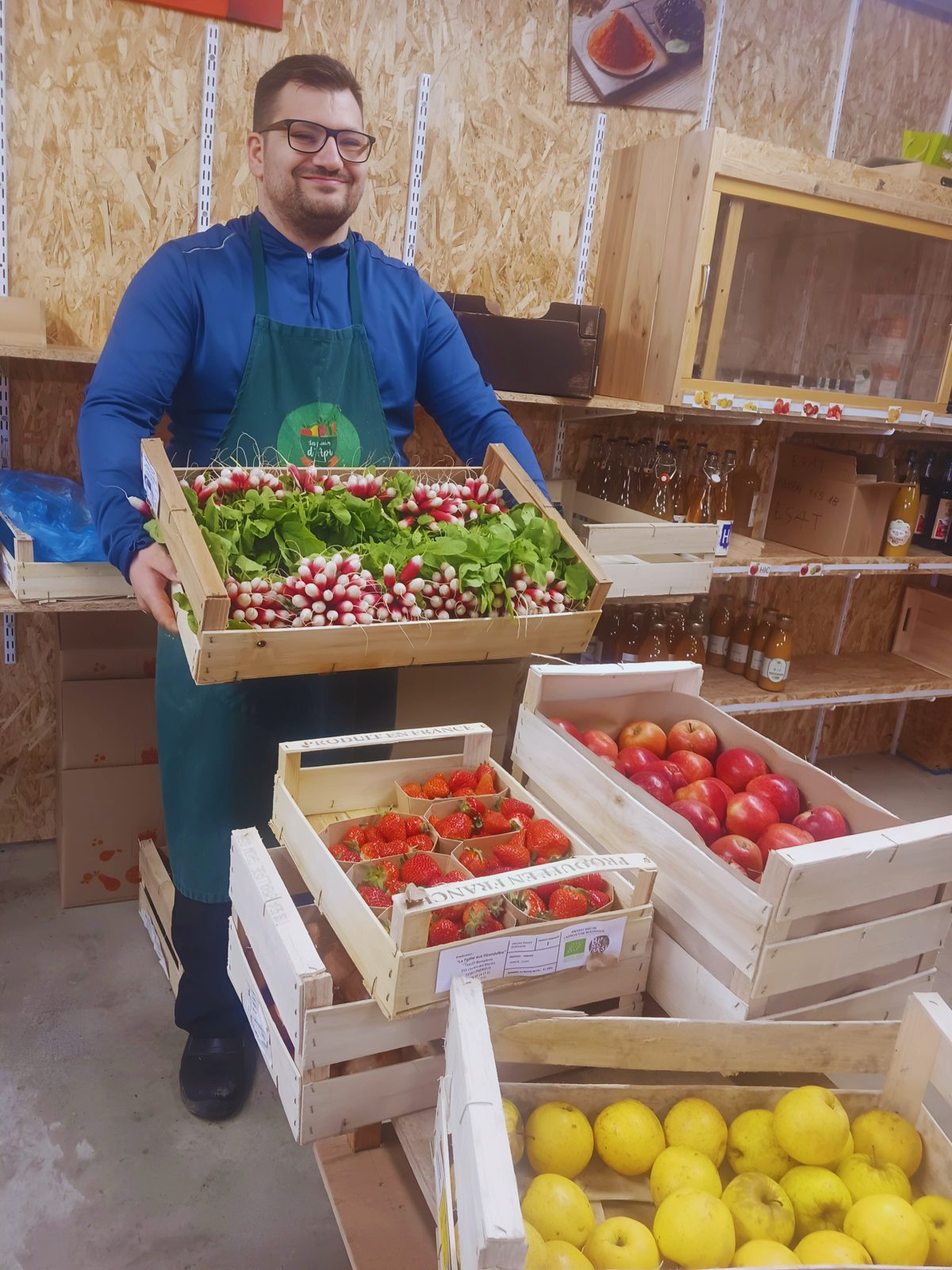 Équipier des Paniers d'Api portant une cagette de radis bio dans l'atelier